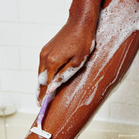 black woman shaving her legs with a razor blade