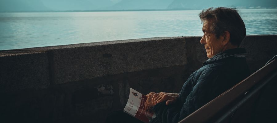 hombre mayor mirando el mar con un libro en la mano