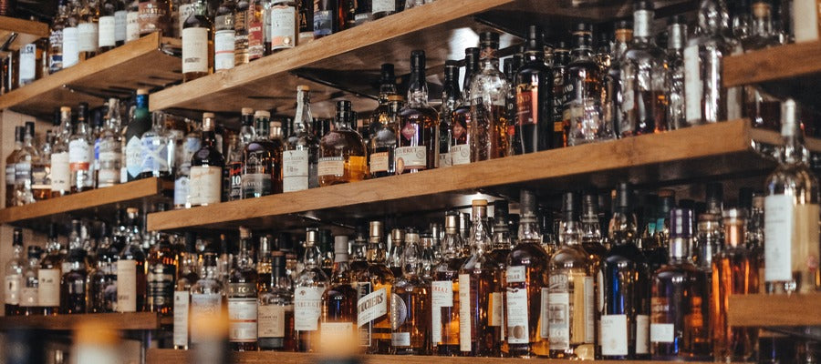 many alcohol bottles on wooden shelves