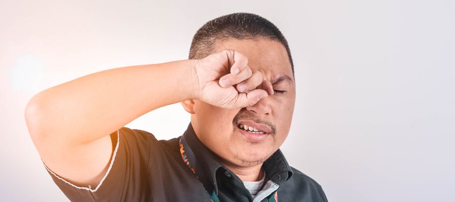 man rubbing his right eye with his hand