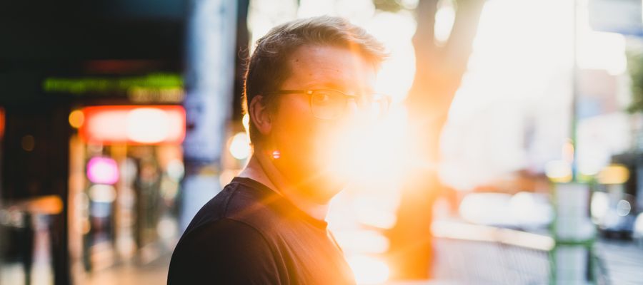 sun glare behind a man with eyeglasses facing the viewer