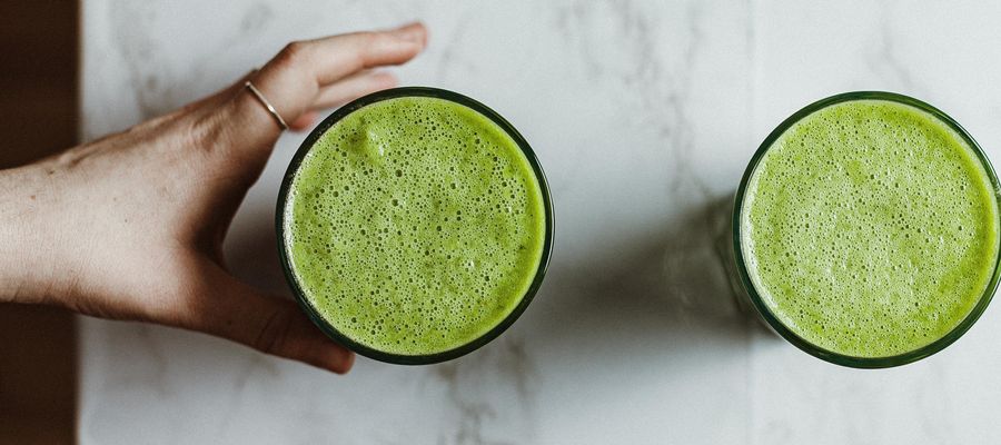 Hand reaching to take a green smoothie in a glass