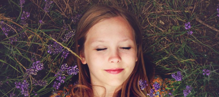 mujer joven tumbada en el campo de flores con los ojos cerrados relajándose