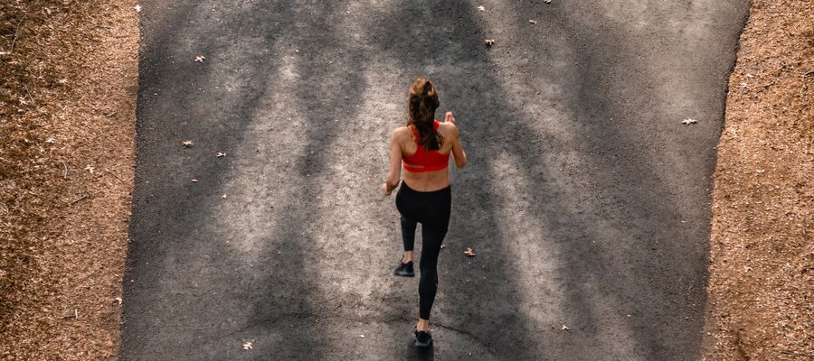 Mujer corriendo en el callejón del parque vista desde arriba