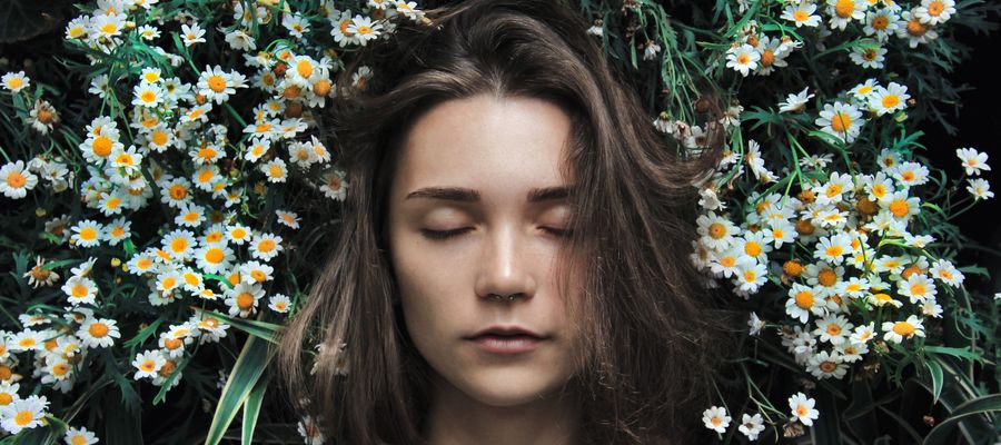 mujer relajada respirando atentamente rodeada de flores