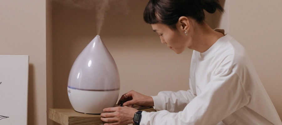 Mujer con camisa blanca instalando un humidificador de habitación grande en casa