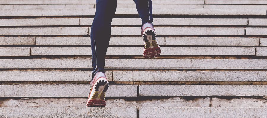 man's legs in running pants and shoes sprinting up steps