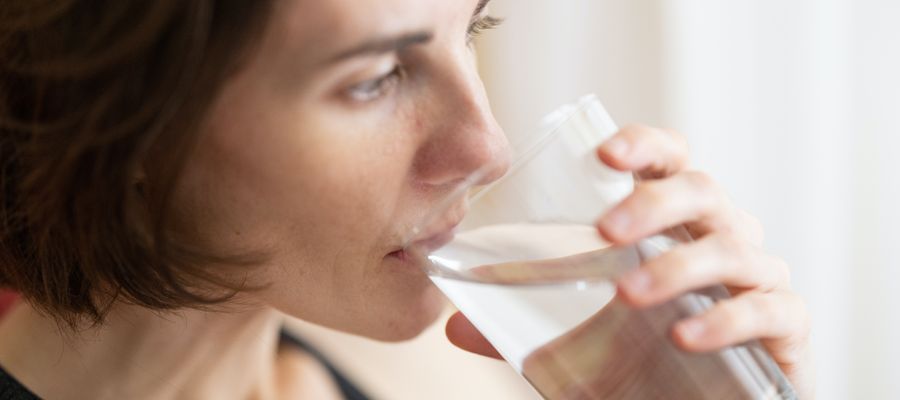 Mujer bebiendo agua de vidrio transparente vista de perfil