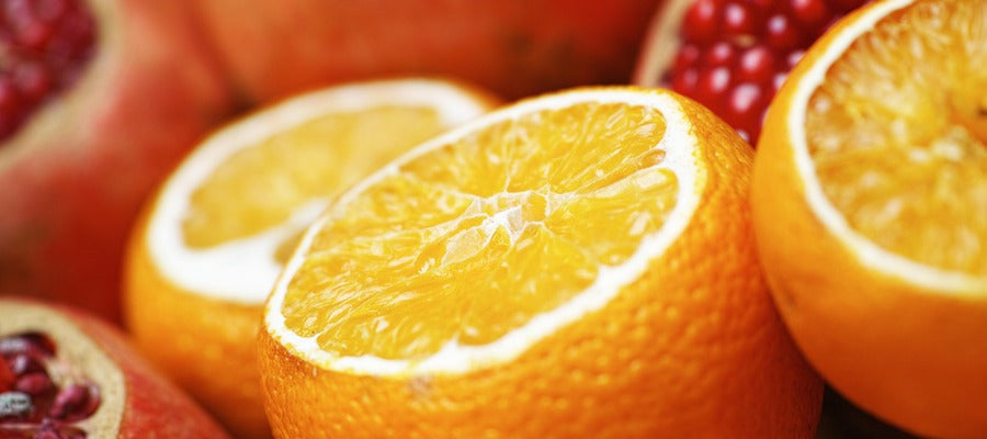 closeup of sliced orange with pomegranates in background