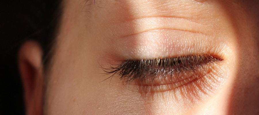closeup of woman's eyelid lighted up by the sun while the rest of her face is in mild shadow
