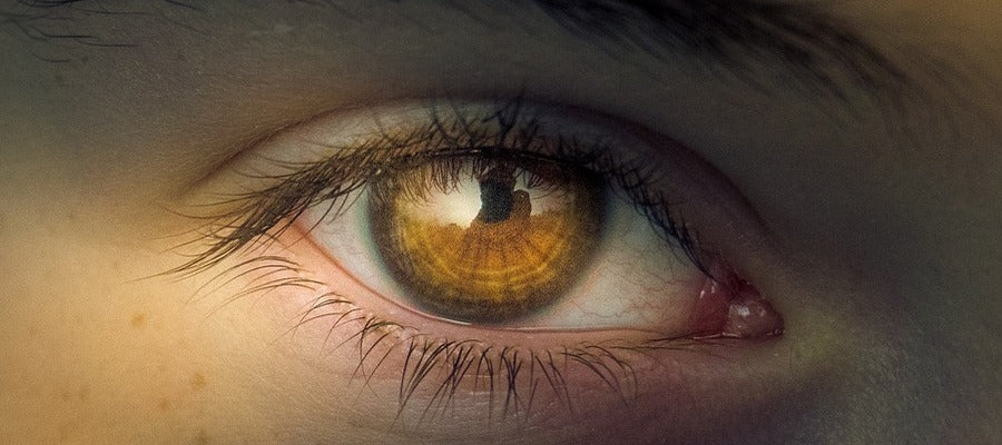 Primer plano del ojo marrón de una mujer con iris iluminado y sombras en la piel.