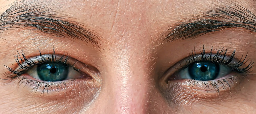 Primer plano de los ojos azules de una mujer con maquillaje y cejas.