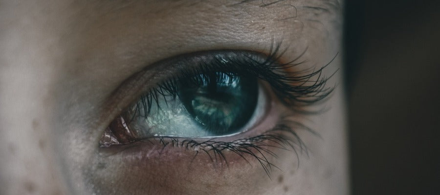 closeup of human eye with long eyelashes looking out to the side