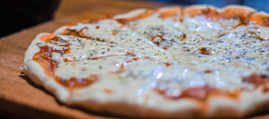 closeup of pizza with melted cheese on top lying on wooden board