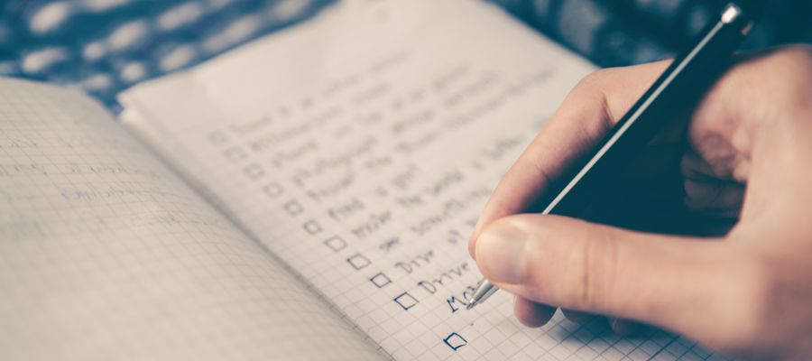 mano que sostiene la pluma escribiendo en un cuaderno