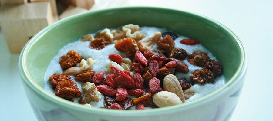 goji berry oatmeal in a green bowl with walnuts and blanched almonds