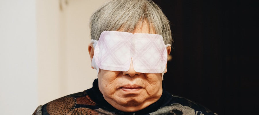 Anciano con pelo gris con máscara que cubre su ojo después de una cirugía ocular