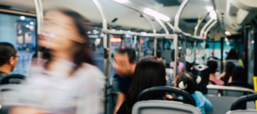 borroso dentro de un autobús con una mujer en primer plano y pasajeros al fondo