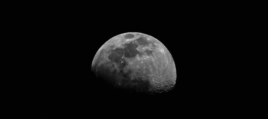 grayscale moon rising out of black background