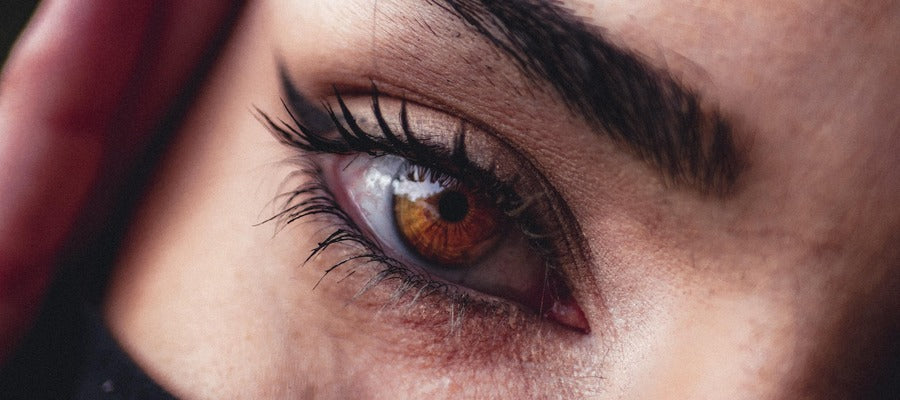 Primer plano de los ojos marrones de una mujer con rímel y delineador de ojos.