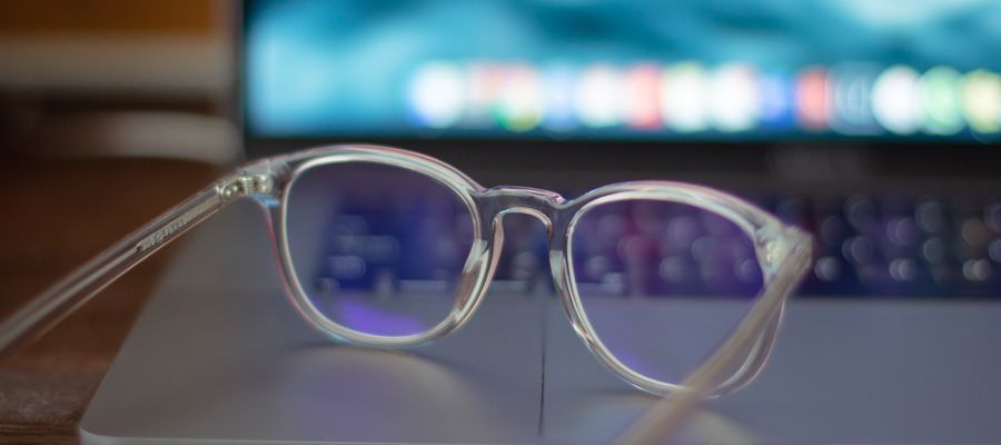 eyeglasses on laptop against blurry keys and screen