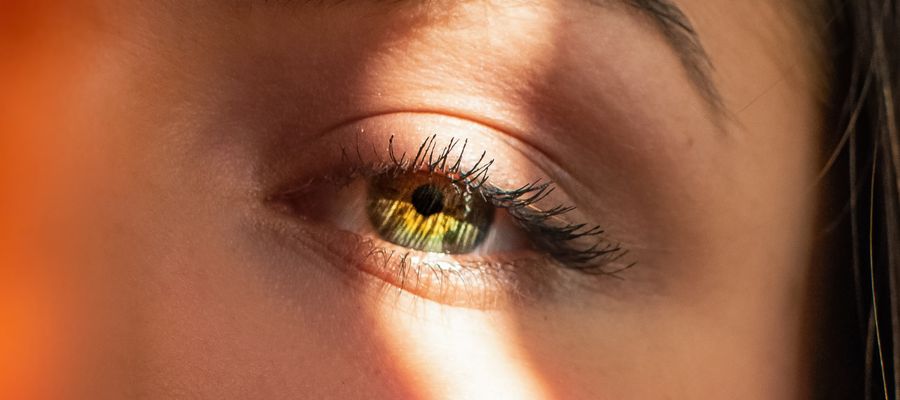 Primer plano del ojo de una mujer iluminado por un rayo de luz.