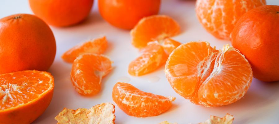 Mandarina pelada y rodajas sobre fondo blanco.