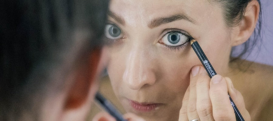 Woman applying eyeliner to her left eye