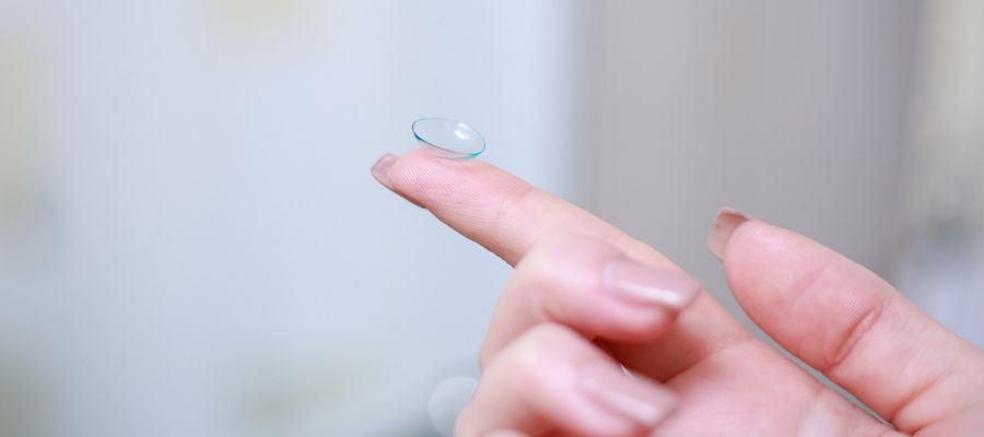 woman's stretched finger holding contact lens