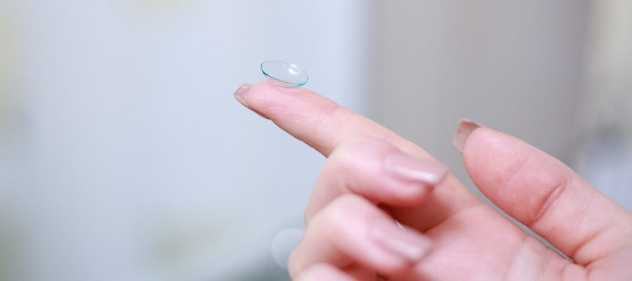 closeup of woman's forefinger holding an upturned contact lens