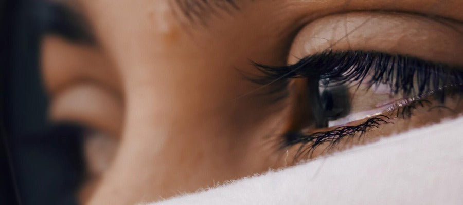 Primer plano de una mujer con ojos llorosos negros mirando hacia otro lado