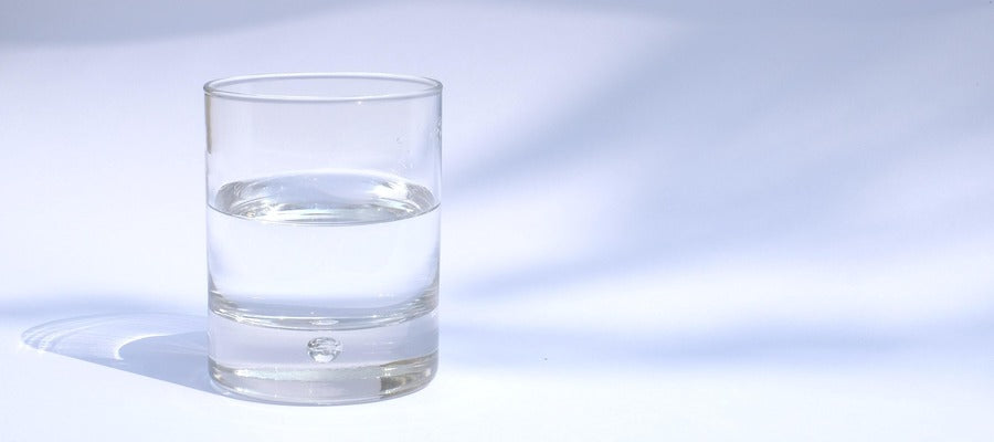 pequeño vaso de agua sobre fondo gris blanco