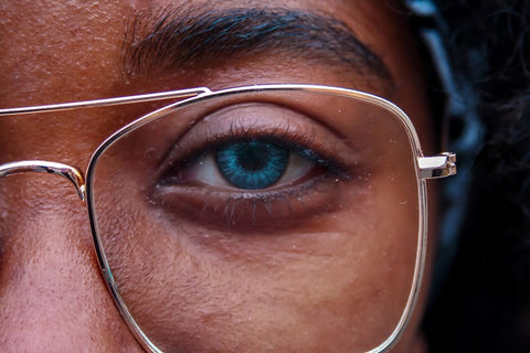 woman's eye behind eyeglass lens half face portrait