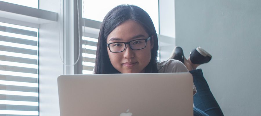 mujer joven con anteojos sentada en el suelo frente a su computadora