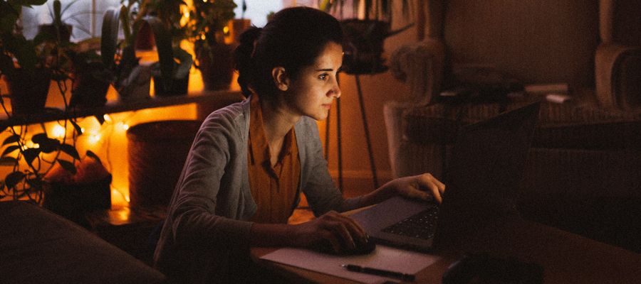 Mujer usando computadora por la noche en una habitación con poca luz