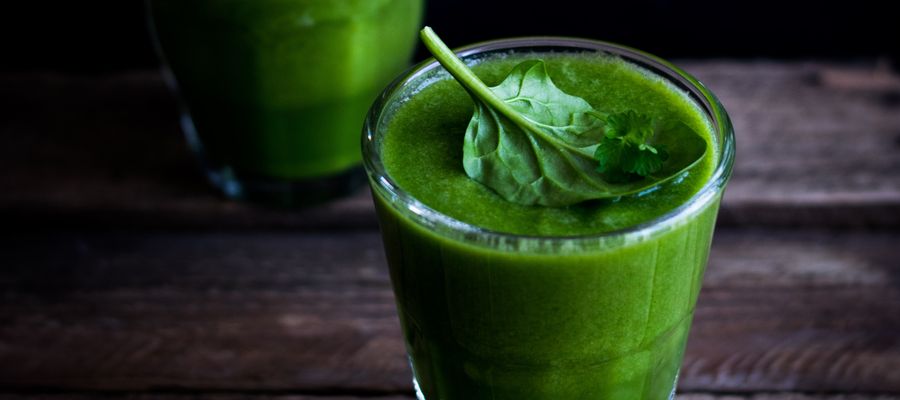 leafy greens smoothie in a glass on a wooden table