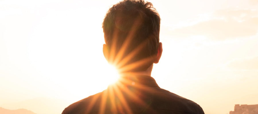 head and shoulders of man seen from behind against glaring sunlight