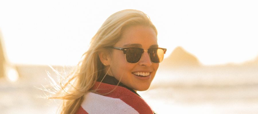 Mujer de pie en la playa con gafas de sol contra un fondo brillante