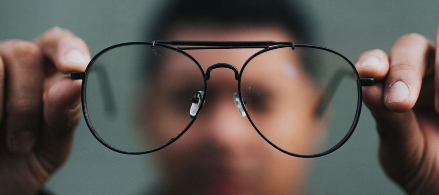 blurry image of man holding a pair of eyeglasses