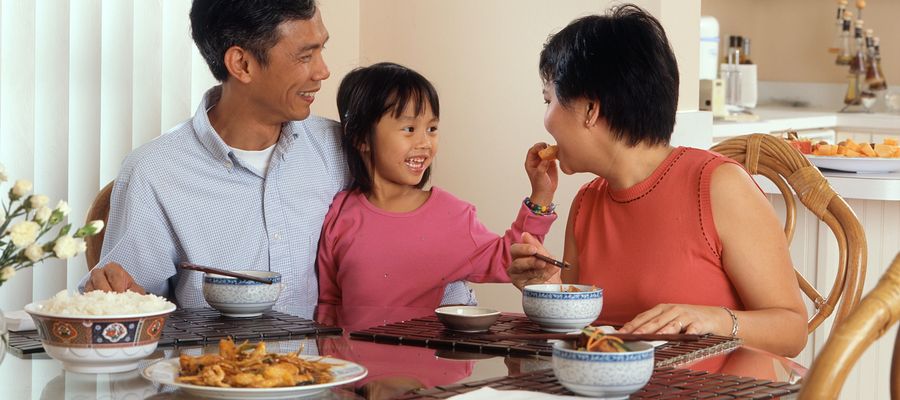 Family at table with little girl giving food to her mother to eat