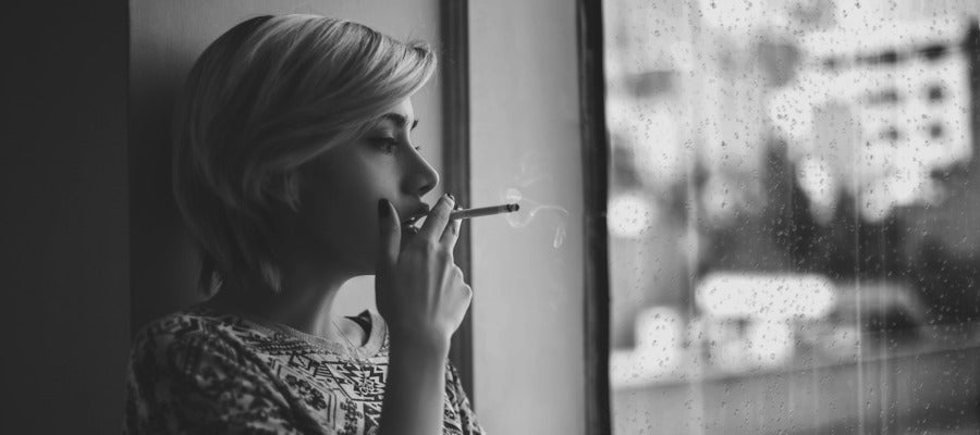 black and white portrait of woman smoking by the window