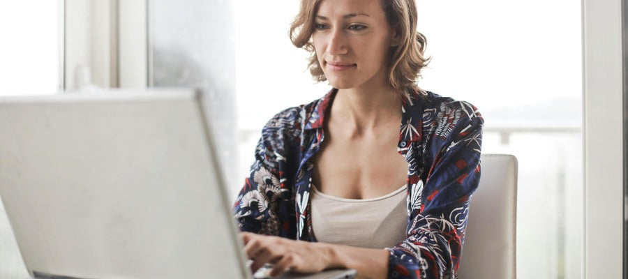 woman working at her computer in white room and smiling slightly after having undergone LASIK surgery