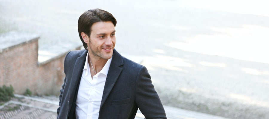 man in elegant suit and white shirt looking to one side and smiling while climbing some steps
