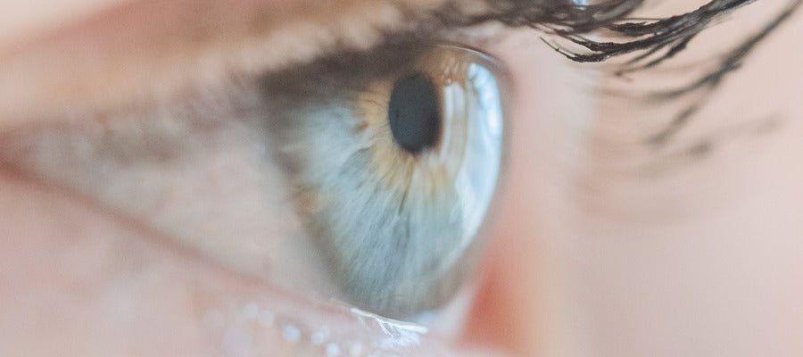 closeup of the eye surface of a blue human eye with long dark lashes