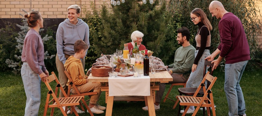 Familia con adolescentes y abuela disfrutando de una comida al aire libre en el jardín.