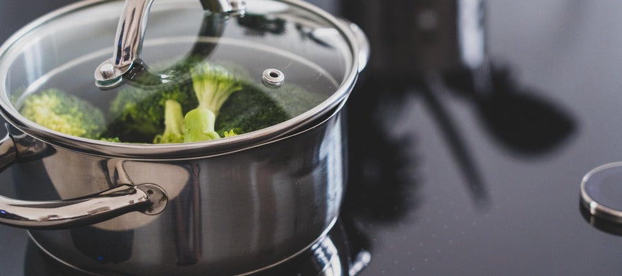 brócoli en una olla de acero inoxidable con tapa de vidrio en la estufa hirviendo