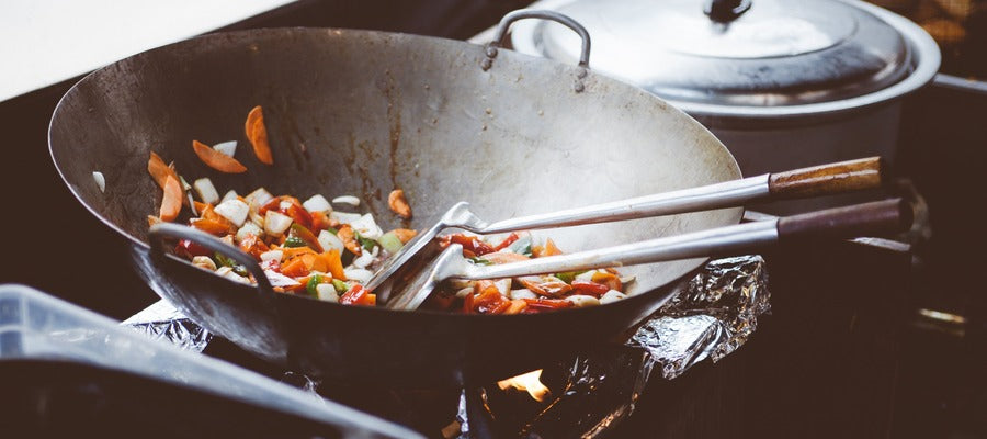 salteado de pollo cocinado en una sartén de acero inoxidable al fuego