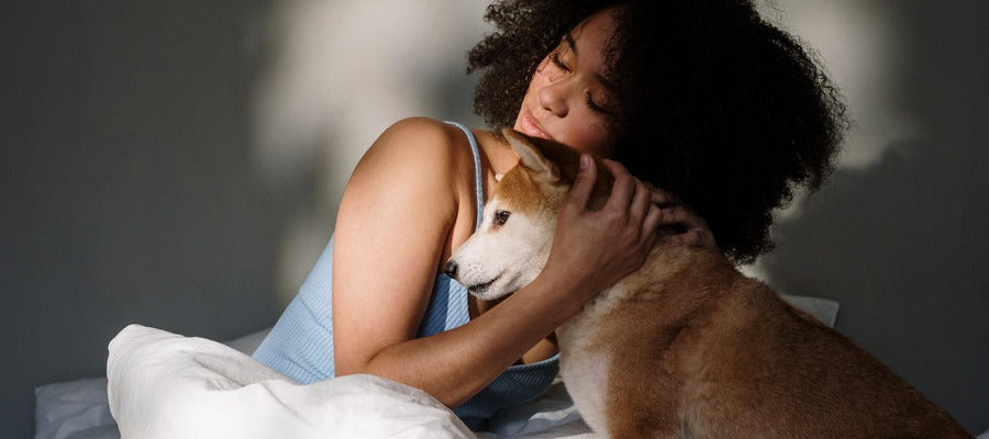 woman hugging dog in bed in the morning after waking