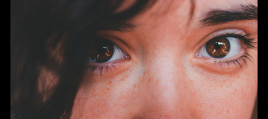 Primer plano de los ojos de una joven con un mechón de pelo negro sobre un ojo.