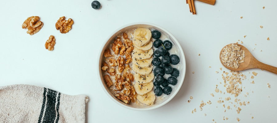 Tazón con avena de arándanos con plátanos y nueces visto desde arriba